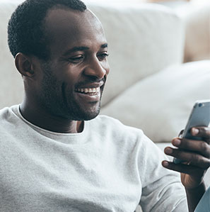 Man smiling holding smart phone while looking at it after using DialCare